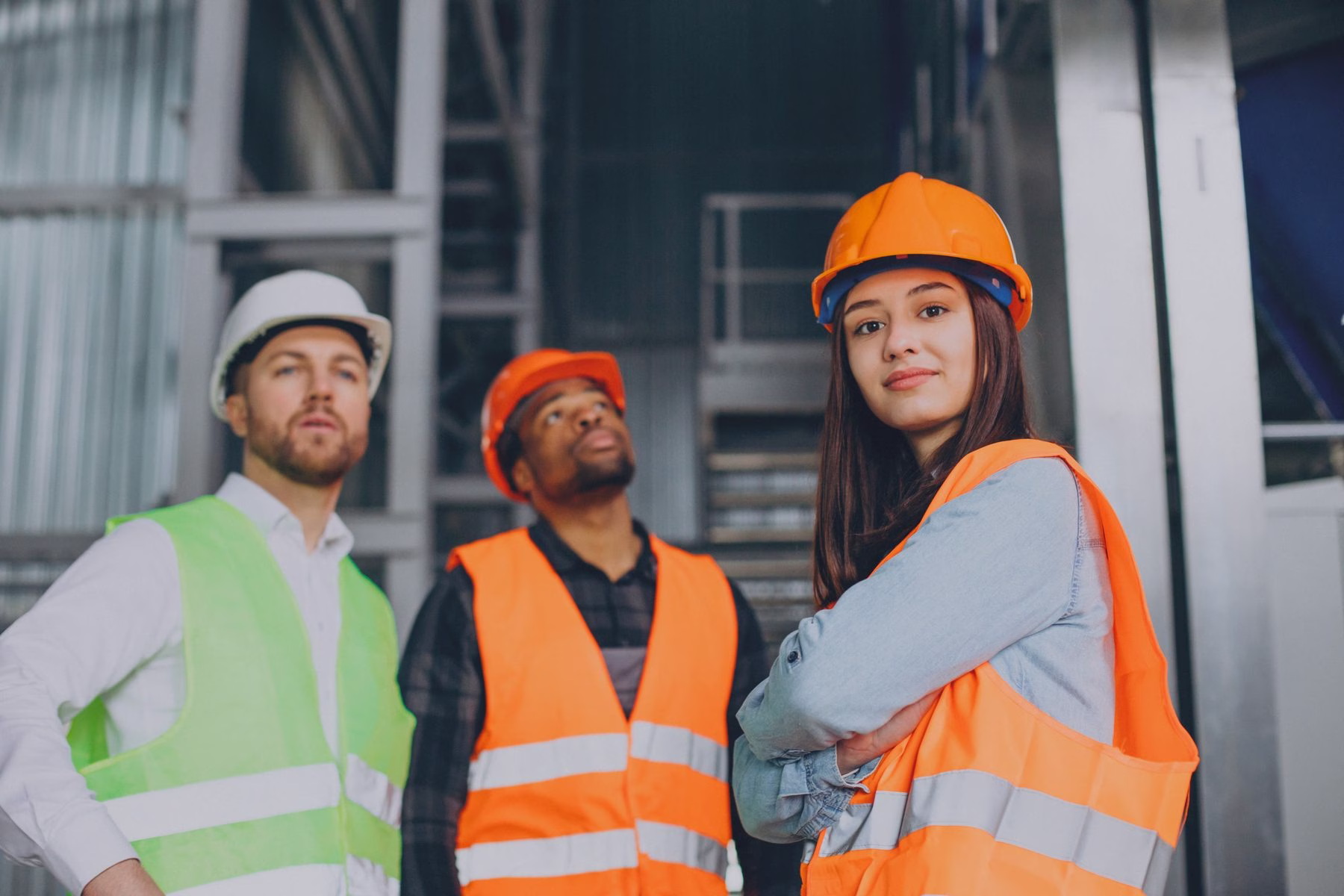 Profissionais de segurança do trabalho com capacetes e coletes em um ambiente industrial