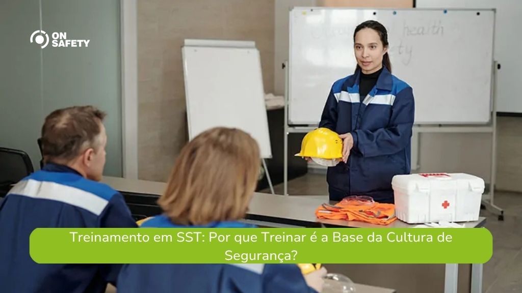 Instrutora de segurança, vestindo uniforme azul, segura um capacete amarelo enquanto ministra treinamento sobre primeiros socorros para dois colaboradores sentados. Na mesa estão equipamentos de segurança e uma caixa de primeiros socorros. Ao fundo, há quadros brancos e um flip chart. No canto superior esquerdo está o logo da OnSafety. Na parte inferior, uma faixa verde traz o texto: “Treinamento em SST: Por que Treinar é a Base da Cultura de Segurança?"