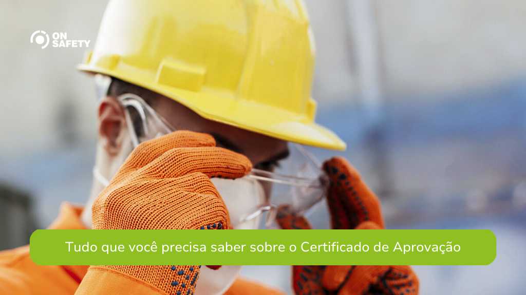 Trabalhador ajustando seus óculos de proteção com luvas e capacete amarelo, em um ambiente industrial. A frase "Tudo que você precisa saber sobre o Certificado de Aprovação" está em destaque na parte inferior da imagem.