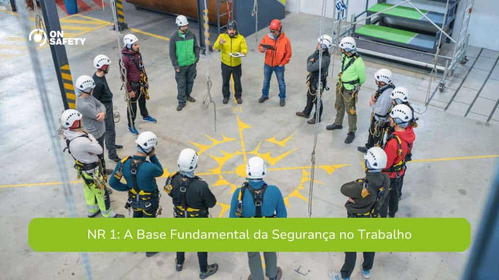 Grupo de trabalhadores em uma roda, equipados com capacetes e cinturões de segurança, participando de uma orientação em um ambiente industrial. A imagem ilustra um treinamento prático de segurança no trabalho, com a frase "NR 1: A Base Fundamental da Segurança no Trabalho" destacada ao centro.