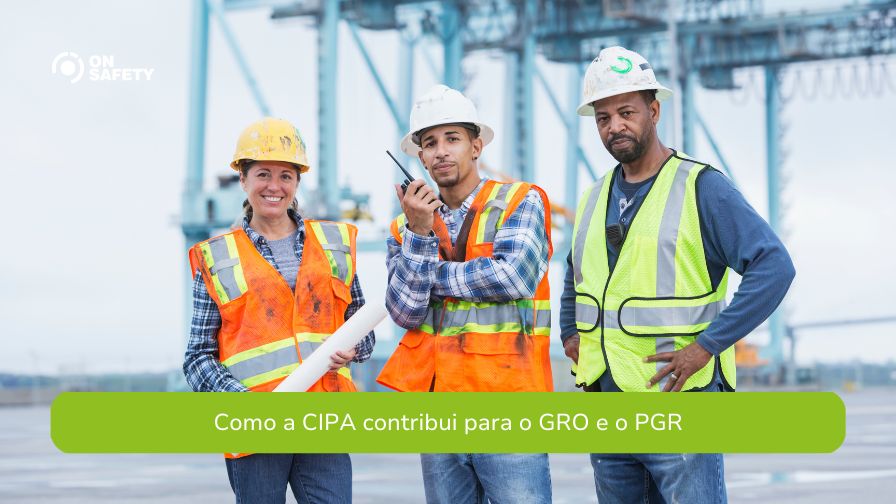 Três trabalhadores da construção civil posam para a foto em um ambiente industrial, usando EPIs como capacetes, coletes refletivos e rádios comunicadores. Ao fundo, estruturas metálicas e guindastes indicam um porto ou terminal de carga. Na parte inferior da imagem, lê-se: "Como a CIPA contribui para o GRO e o PGR".