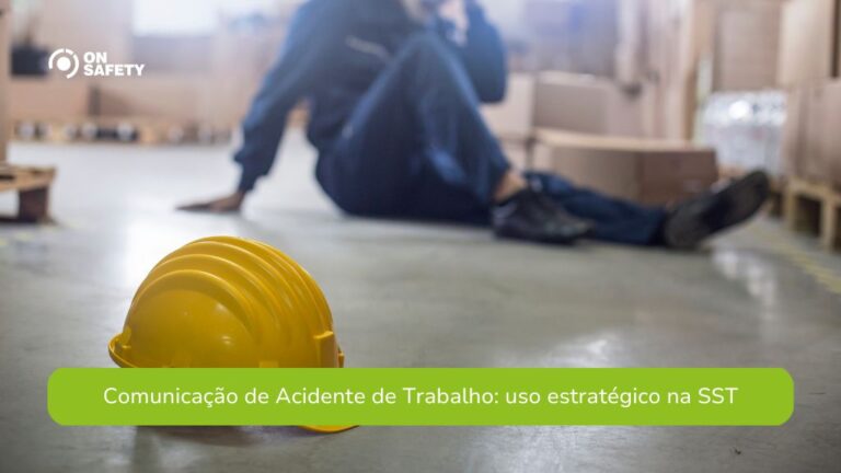 Capacete amarelo no chão de um galpão, com um trabalhador ao fundo sentado no chão após um possível acidente. O ambiente contém caixas e paletes, sugerindo um local de armazenamento. No canto superior esquerdo, está o logo da OnSafety. Na parte inferior da imagem, uma faixa verde exibe o texto: "Comunicação de Acidente de Trabalho: uso estratégico na SST".