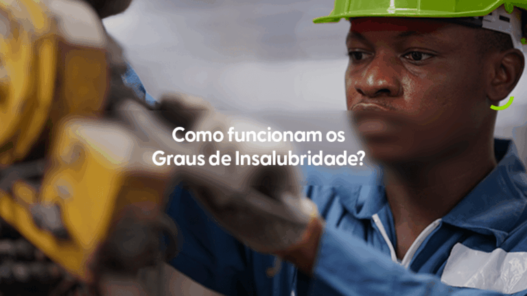 Imagem em close-up de um trabalhador em um ambiente industrial, vestindo um uniforme azul e utilizando um capacete de segurança verde limão. O profissional está focado em sua atividade, operando um equipamento mecânico amarelado que aparece em primeiro plano, de forma desfocada. Um pequeno detalhe em arco verde estilizado está posicionado no canto direito, na altura do pescoço do trabalhador. No centro da imagem, uma faixa cinza transparente destaca o título em branco: "Como funcionam os Graus de Insalubridade?".